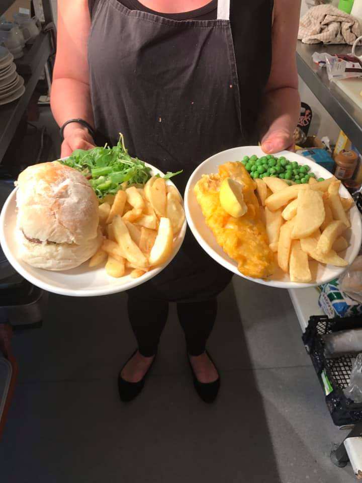 Two plates of fish and chips being served
