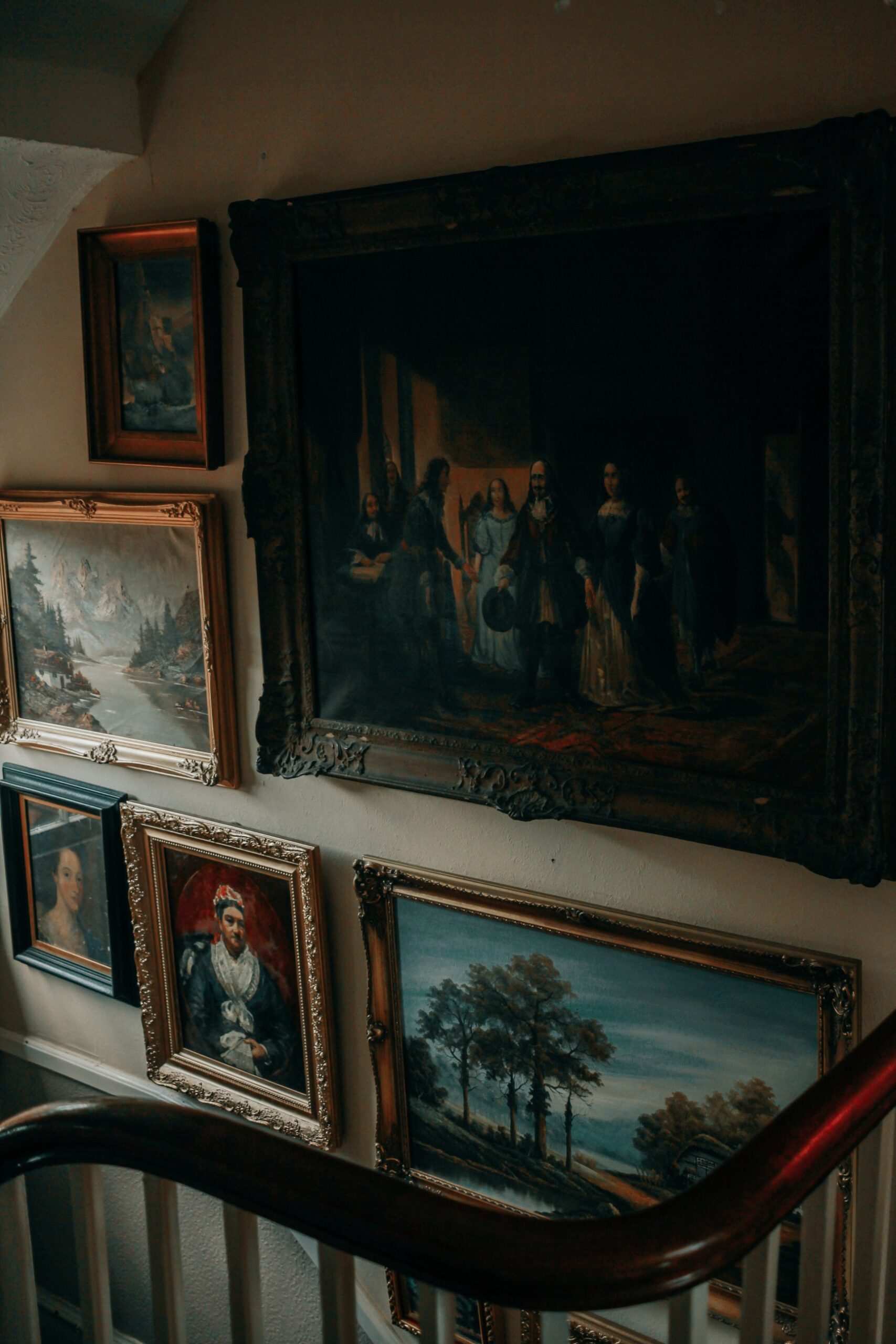 Oil paintings in gilt frames on a hallway wall