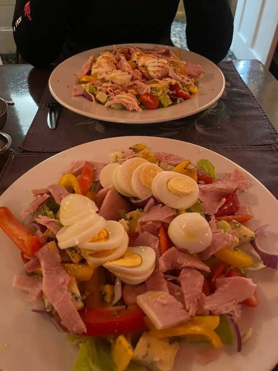 A large salad with ham, boiled eggs and peppers