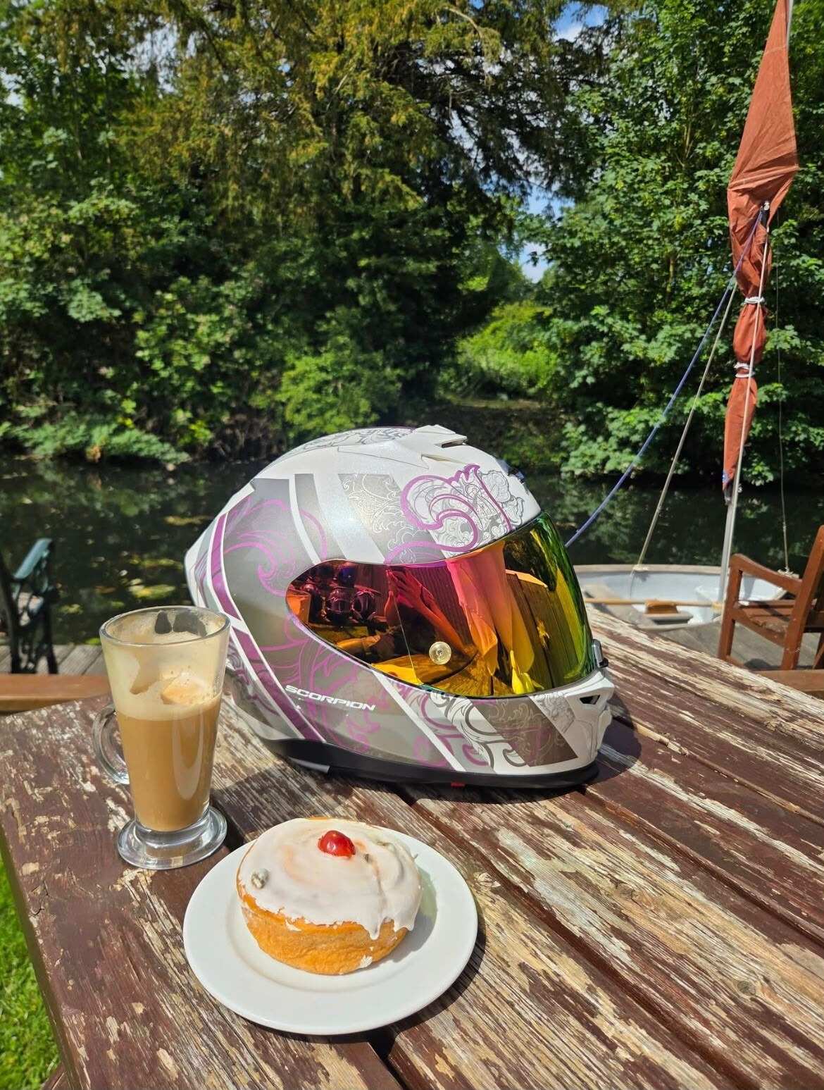 A latte and an iced bun on a riverside table