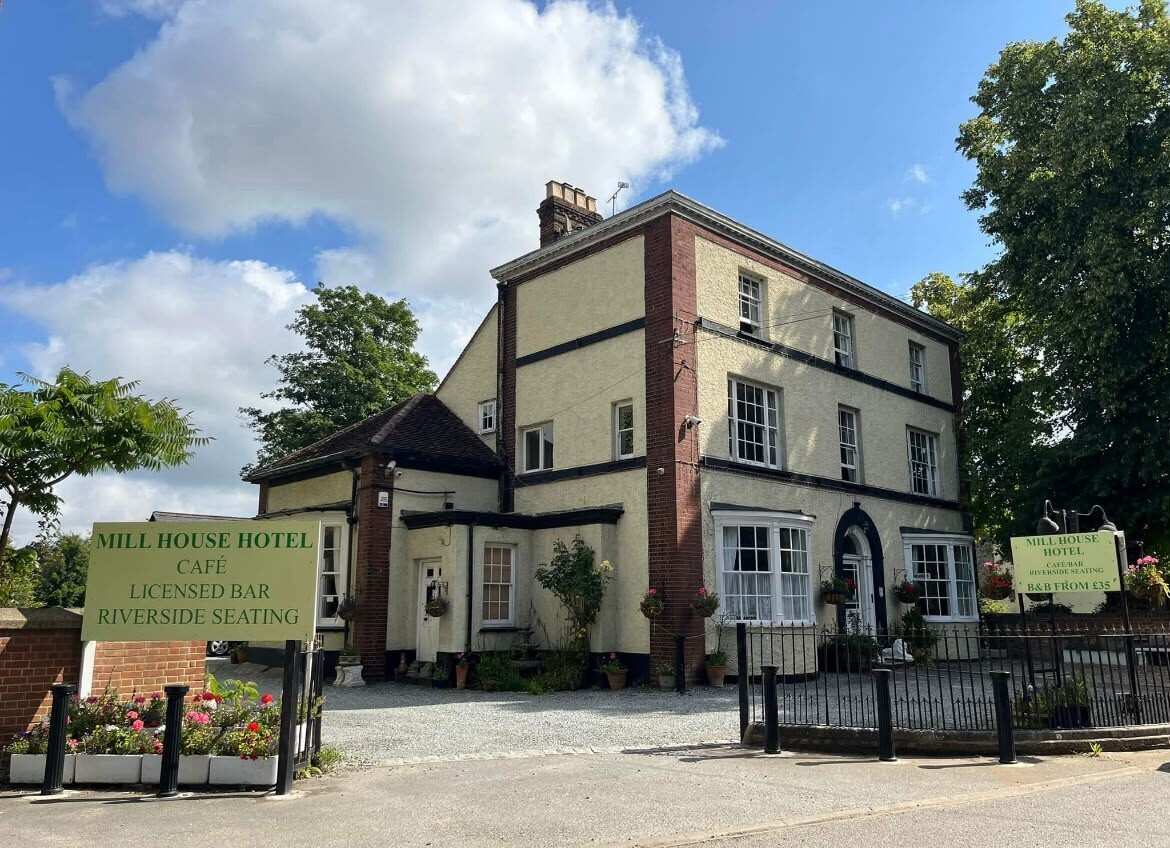 The front of the Millhouse Hotel on a sunny day, with its sign for the café, licensed bar and riverside seating