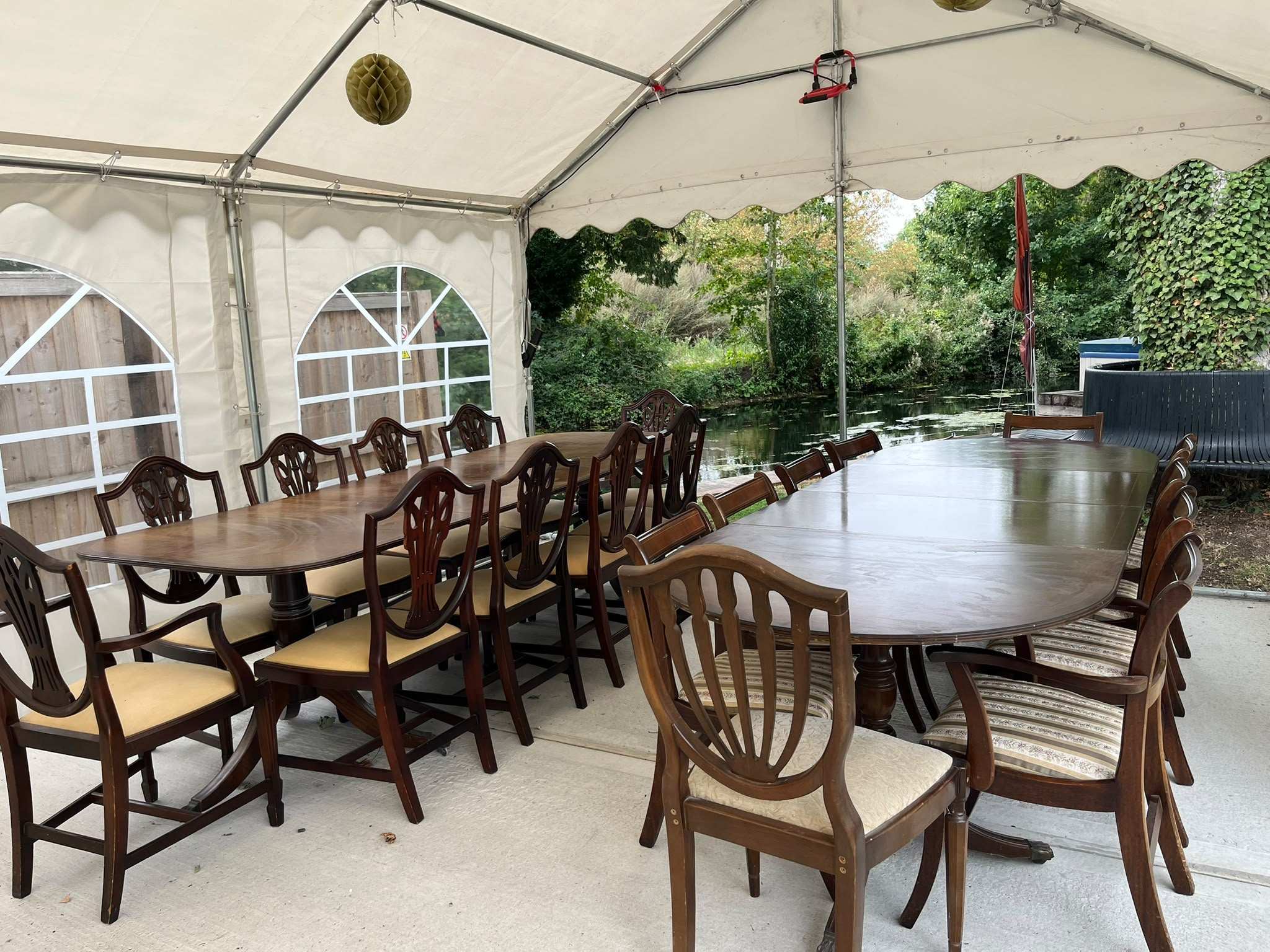 Inside the marquee: long dining tables with wooden chairs, the garden through the windows